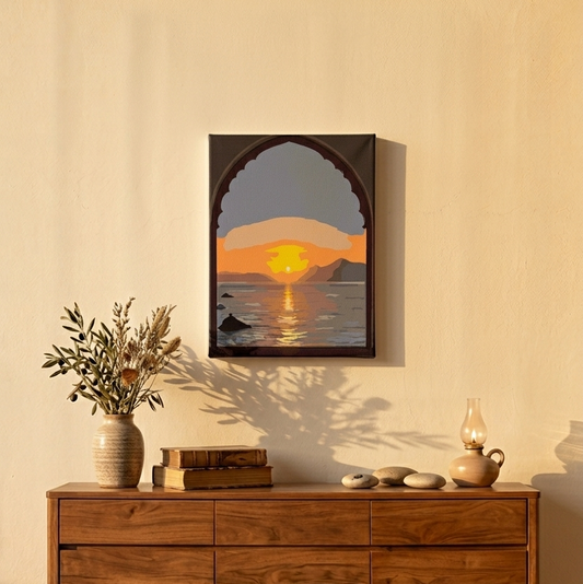 Une console en bois de noyer moderne dans un salon éclairé par le soleil couchant. Sur le meuble sont posés un vase en céramique avec de branches séchées, des livres vintage, des galets et une lampe à huile allumée. Au-dessus, un petit tableau (30x20 cm) accroché au mur représente un coucher de soleil sur la mer à travers une arche de style mauresque.